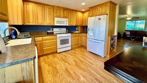 A kitchen with wooden cabinets, a white refrigerator, a stove, and a microwave.