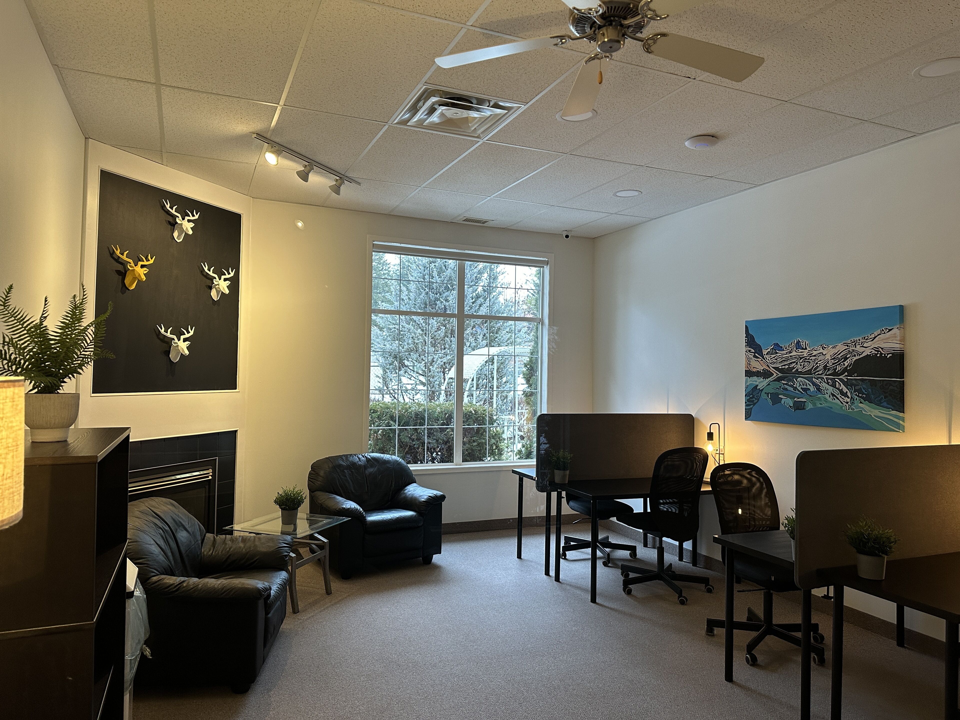 A conference room with a large window, a fireplace, and a ceiling fan.