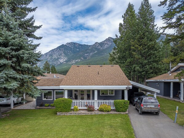 A house with a porch, a driveway, and a mountain backdrop.