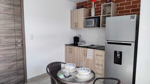 A compact kitchen with a microwave, refrigerator, and a small dining area with a table and chairs. - Jacuzzi Getaway, in the Heart of Zone 4 (Ciudad de Guatemala)