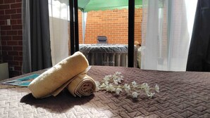A room with a bed, a window with a view of a brick wall and a green umbrella outside. - Jacuzzi Getaway, in the Heart of Zone 4 (Ciudad de Guatemala)