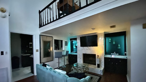 Ein modernes Wohnzimmer mit einer Couch, einem Kamin, einem Fernseher und einem Balkon.