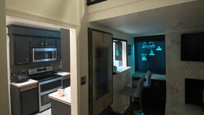 Eine moderne Küche mit Mikrowelle, Herd und Backofen. Ein Essbereich mit Tisch und Stühlen ist vorhanden. Eine Treppe führt auf eine obere Ebene.