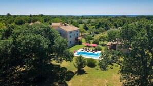 A large stone building with a swimming pool and outdoor seating area surrounded by lush greenery. - Beach front home in Pula (Pula)