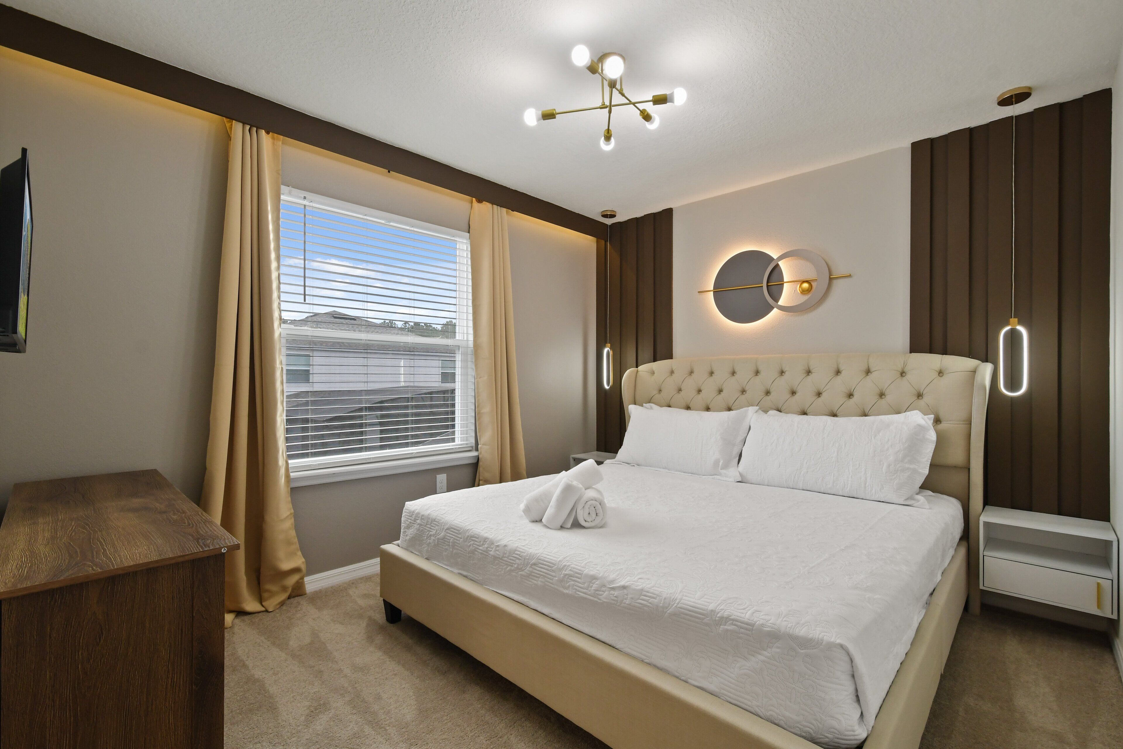 Une chambre à coucher avec un grand lit, une table de chevet en bois, une horloge murale ronde et une fenêtre avec des rideaux.