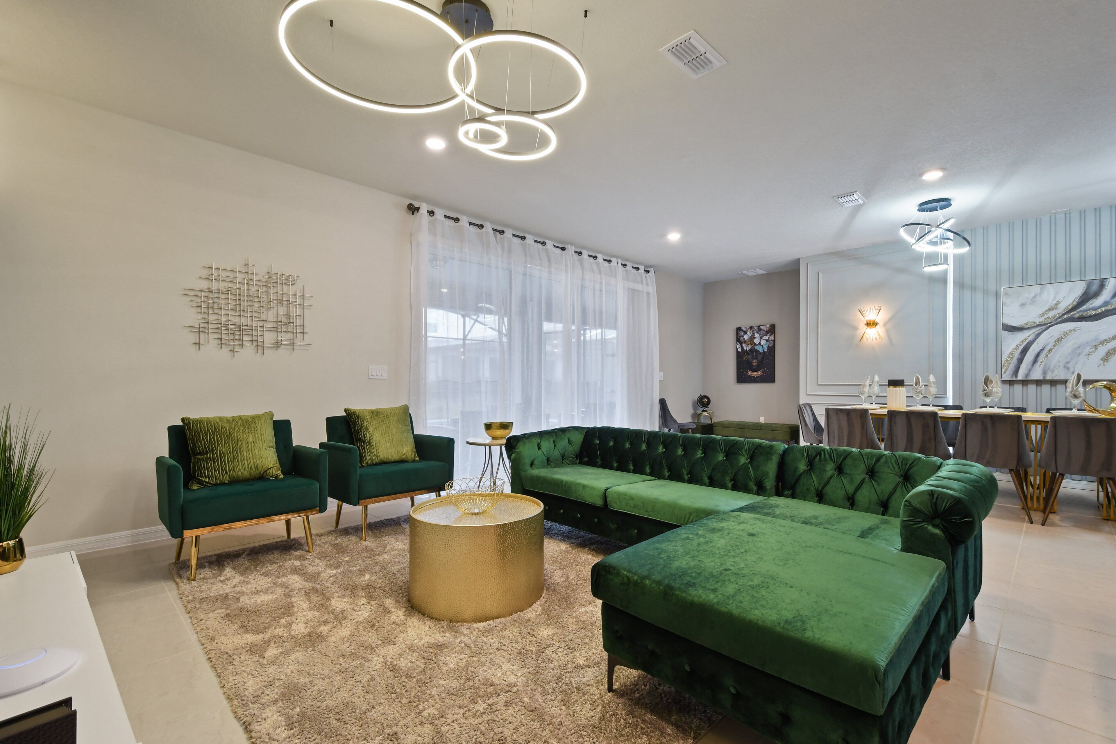 A modern living room with a sectional sofa, two armchairs, a round coffee table, and a dining area with a table and chairs.