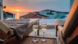 A balcony with two lounge chairs, a wooden table, and two glasses of white wine. - Pet friendly home in Razanj (Razanj)