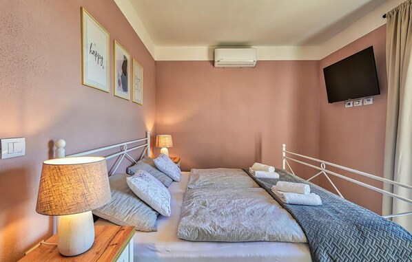 Une chambre à coucher avec un lit, des lampes de chevet, un téléviseur à écran plat et des œuvres d’art encadrées accrochées au mur.