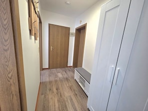 Ein Flur mit einer Holztür, einem weißen Schrank und einer Bank.