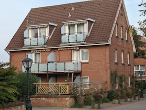 Ein zweistöckiges Ziegelhaus mit Balkon, einer Veranda mit Holzlattenzaun und einer Straßenlaterne.