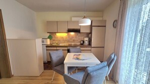 Una cocina compacta con comedor, microondas, cafetera y una lámpara colgante.