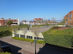 A parking area with a paved road, a lamp post, and a hedge. - Haus Ekke Nekkepenn I, Whg. 6 - Haus Ekke Nekkepenn I, (Wyk auf Föhr)