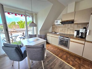 Eine moderne Küche mit Essbereich, großen Fenstern und Blick ins Freie.