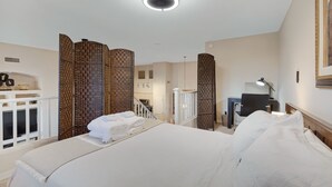 Habitación de hotel con una cama grande, un escritorio, una silla y vistas al baño y la cocina.