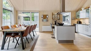 Une cuisine moderne dotée d’un îlot central, de planchers en bois et de grandes fenêtres.