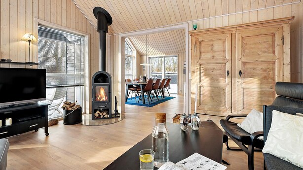 Un salon moderne doté d’une cheminée, de murs en bois, d’un coin repas et d’une grande porte en bois.