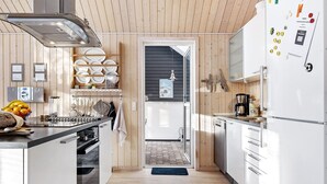 Une cuisine moderne avec des murs en bois, un îlot central et une vue sur la salle à manger.