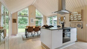 Une cuisine moderne dotée d’un îlot central, de grandes fenêtres et de lambris en bois.