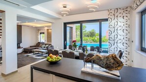 A modern interior with a dining area, a large window overlooking a pool, and a unique centerpiece on the table.