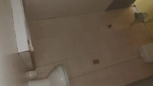 Ein Badezimmer mit Toilette, einem kleinen Mülleimer und einer Wandleuchte.