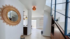 A modern interior with a large mirror, a wicker basket, and a staircase.