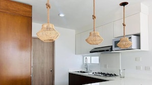 A modern kitchen with a white countertop, wooden cabinets, and a central island with chairs.