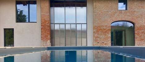 Un bâtiment doté d’une piscine, de grandes fenêtres et d’une façade en briques.
