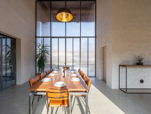 A spacious dining area with a long wooden table, multiple chairs, and a large window providing natural light. - We Rural by Interhome (Poirino)