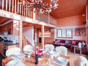 Une cabane en bois spacieuse comprenant un coin repas, une cuisine et un salon.