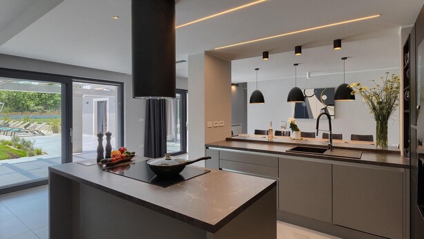 A modern kitchen with a central island, pendant lighting, and a view of the outdoors.