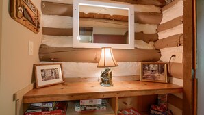 L’intérieur d’un chalet rustique, avec une étagère en bois, une lampe, des tableaux encadrés et un miroir.