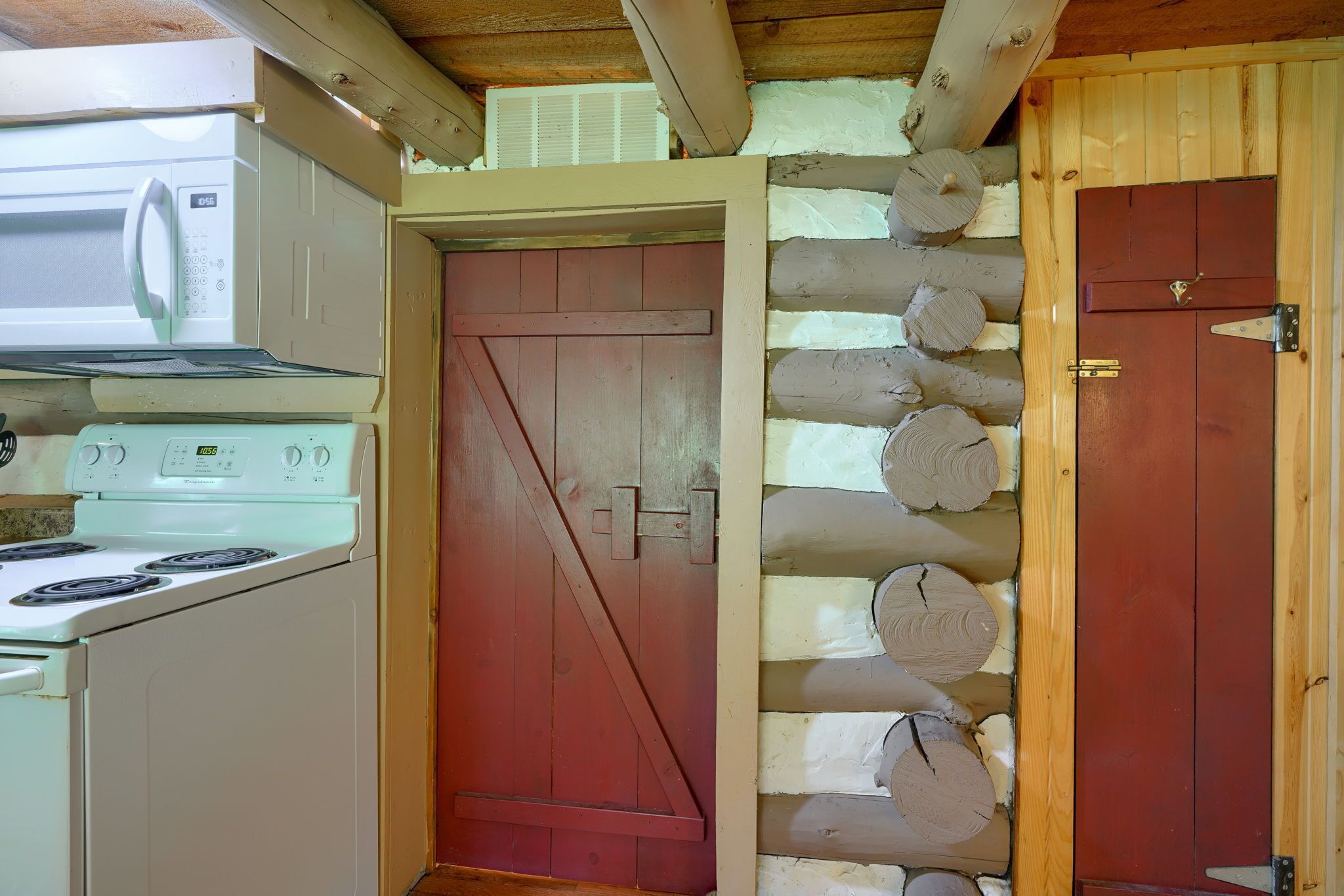 Eine Küche mit einem weißen Herd, einer roten Tür und einer Holzwand.
