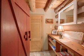 A wooden interior with a red wardrobe, a mirror, and a shelf with books and a lamp. - Waterfall Cabin | Private Trails, Hot Tub (South Bloomingville)