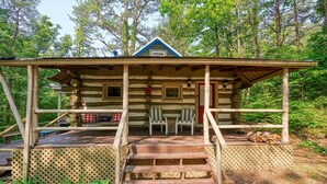 Eine rustikale Holzhütte mit Veranda, zwei Stühlen und einem kleinen Tisch.