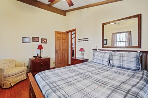A bedroom with a bed, a chair, a dresser, a mirror, and a door.