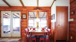 Un comedor de madera con una mesa, sillas, un ventilador de techo y una puerta que da al exterior.