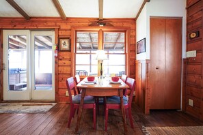 A wooden dining room with a table and chairs, a ceiling fan, and a door leading outside.
