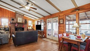 A cozy cabin interior with a fireplace, a television, and a dining area.