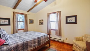 A bedroom with a bed, a chair, a window, and a ceiling fan.