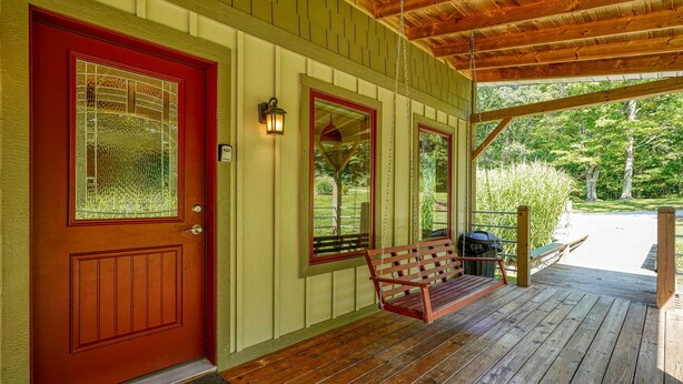 A wooden porch with a red door, a bench, and a hanging light fixture. - Songbird Cabin | Hocking Hills, Private Trails (South Bloomingville)