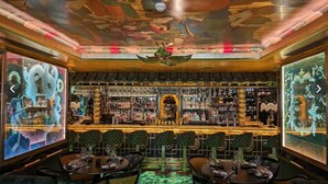 Ein Barbereich mit traditionellem asiatischen Design, der ein Holzbalken-Untergestütztes Zimmer, eine Bar und Sitzgelegenheiten mit grünen Polsterstühlen zeigt.