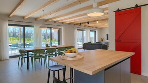 Una cocina moderna con una isla de madera, sillas verdes y una puerta de estilo granero roja.