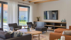 Una sala de estar moderna con un televisor grande, asientos cómodos y vistas al exterior.