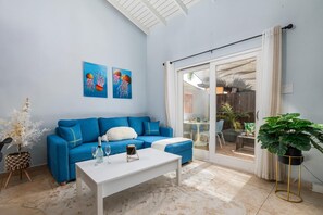 Ein modernes Wohnzimmer mit einem blauen Sofa, einem weißen Couchtisch und Kunstwerken an der Wand.
