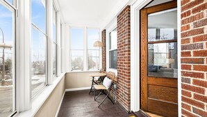 A narrow hallway with a wooden door, a small table with chairs, and large windows. - Lakeside Condo | Minutes from Downtown Duluth (Duluth)