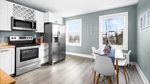 A modern kitchen with stainless steel appliances, a dining area with a table and chairs, and large windows providing views of the outside. - Lakeside Condo | Minutes from Downtown Duluth (Duluth)