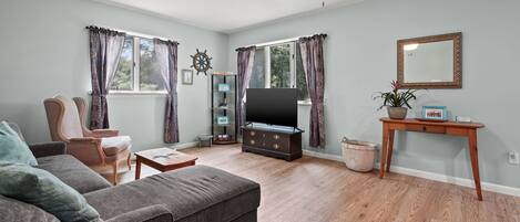 A living room with a sofa, a television, a wooden coffee table, and a ceiling fan.