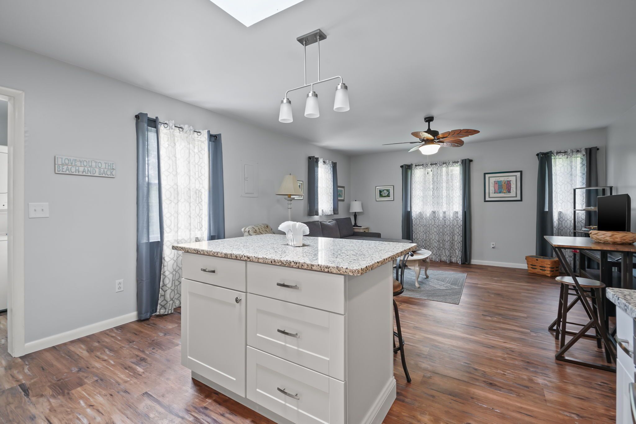 A spacious kitchen with a central island, a ceiling fan, and a dining area with a table and chairs.