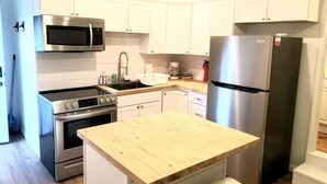 A modern kitchen with white cabinets, stainless steel appliances, and a wooden countertop. - Magnolia #3 @ Copper Johns Resort (Lakeview)