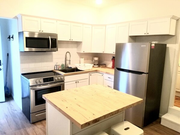 Una cocina moderna con armarios blancos, electrodomésticos de acero inoxidable y encimera de madera.